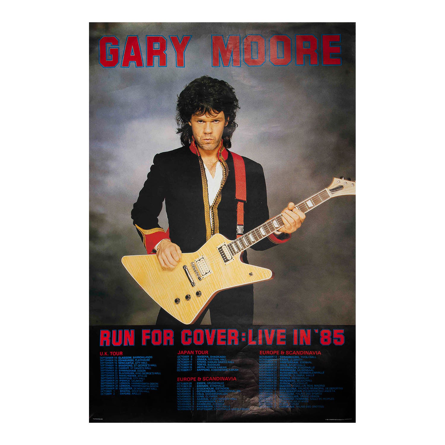 A Gary Moore concert poster featuring a photo of the musician playing an electric guitar, with bold red text reading 'GARY MOORE' at the top and 'RUN FOR COVER-LIVE IN '85' at the bottom.